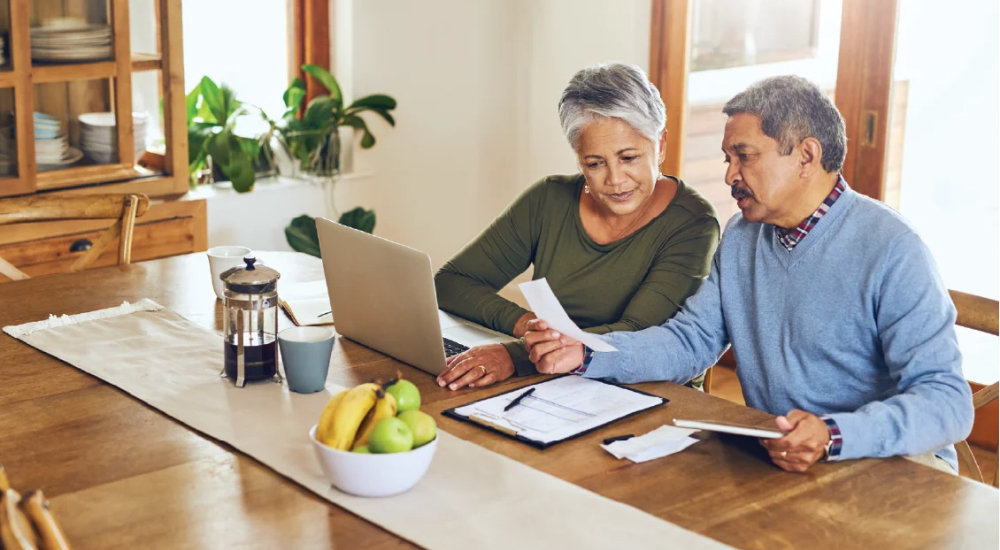 A man and woman with a laptop and a notebook and looking at a receipt